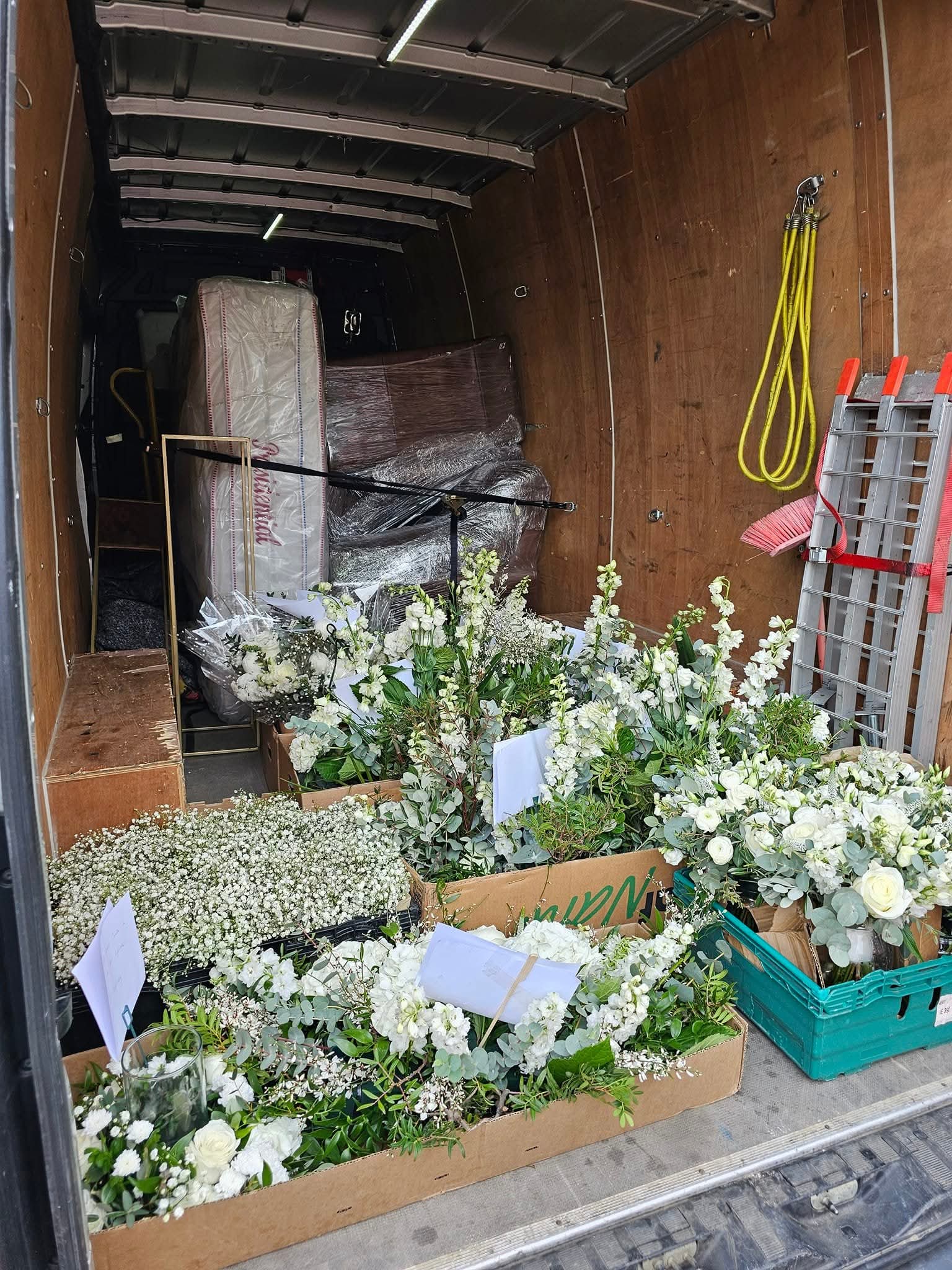 White flower arrangements loaded in boxes inside the delivery van