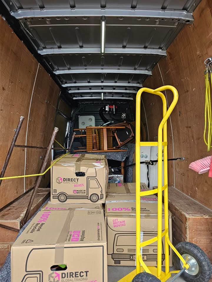 Moving boxes and a yellow sack truck inside the van